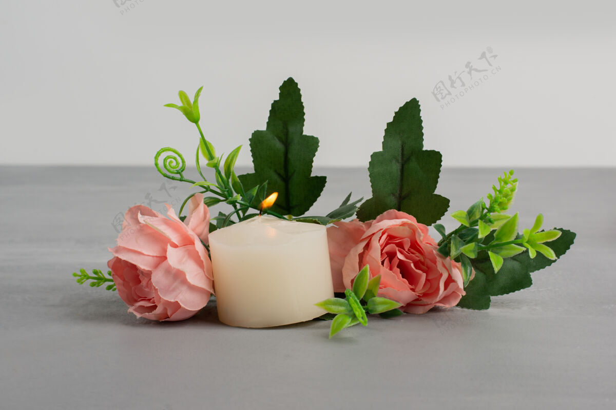叶粉红色的玫瑰 绿叶和蜡烛放在灰色的桌子上五颜六色花玫瑰