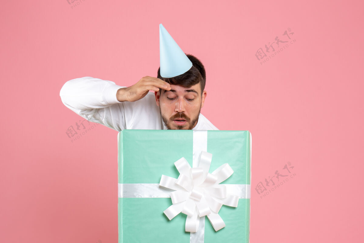 聚会正面图：年轻男性站在礼物盒内 浅粉色照片 人类情感圣诞睡衣派对礼物盒子爱国