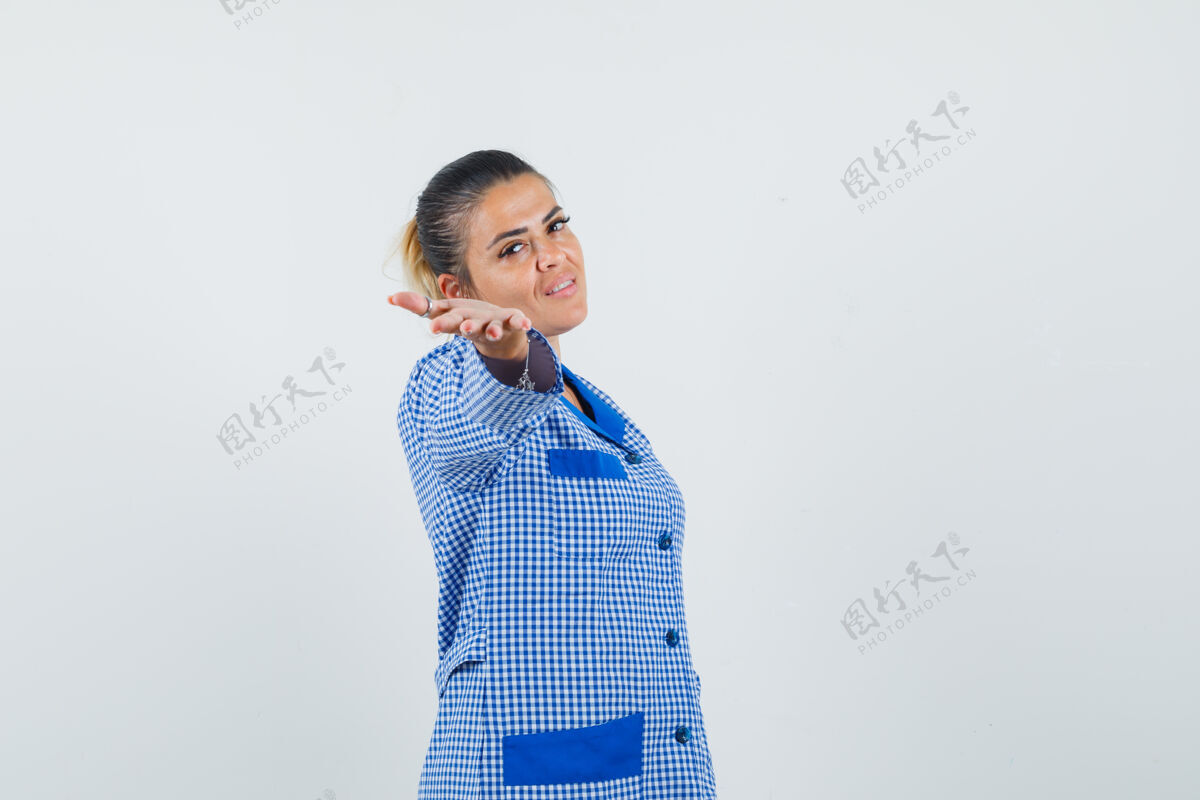 手穿着蓝色方格布睡衣衬衫的年轻女子把手伸向相机 看起来很漂亮正视图伸展漂亮脸