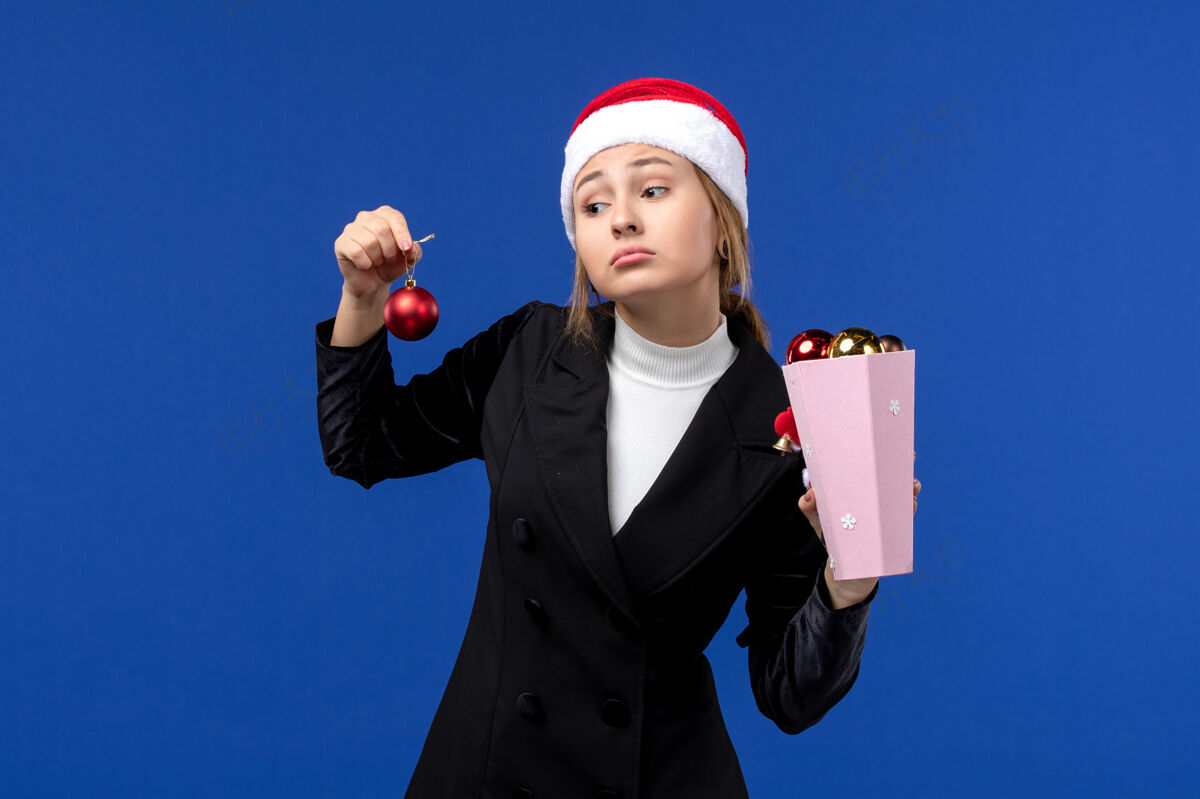 小姐前视图年轻女士拿着蓝色墙上的树玩具情绪新年假期蓝色观点举行工人