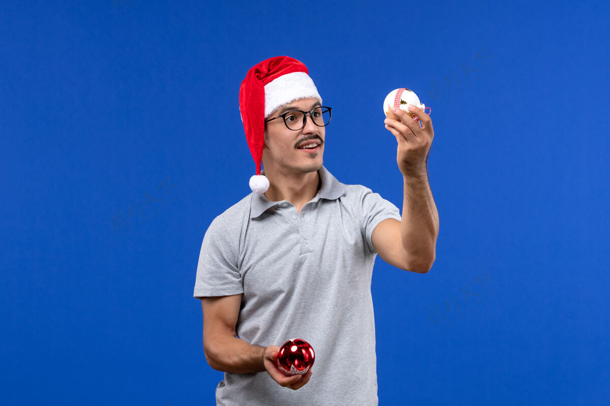 男人正面图：年轻男性手持塑料树玩具 蓝色背景 男性节日 新年圣诞节前面成人