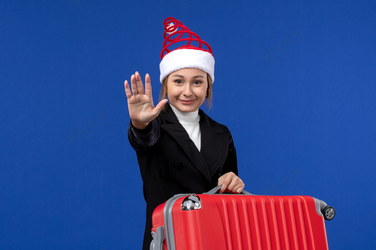 年轻女性蓝墙度假女飞机上带着大红包的年轻女性的正面图前面飞机帅哥