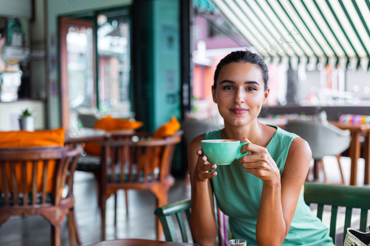 优雅可爱 优雅 平静 快乐的女士 穿着绿色夏装 坐在咖啡馆里喝咖啡 享受早晨女士举行休闲