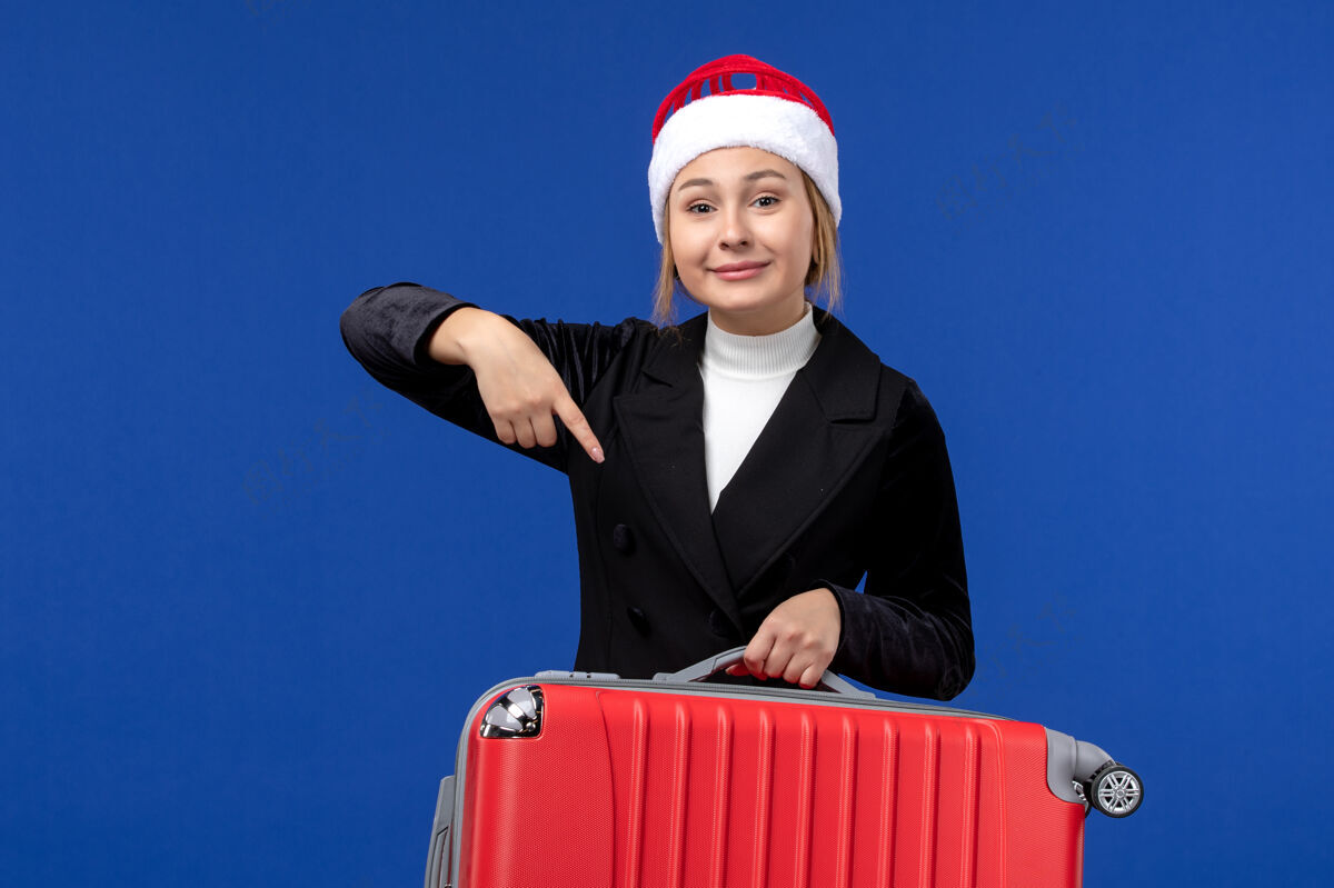 工作正面图年轻女子提着红包上蓝墙旅游度假的女人圣诞节风景背