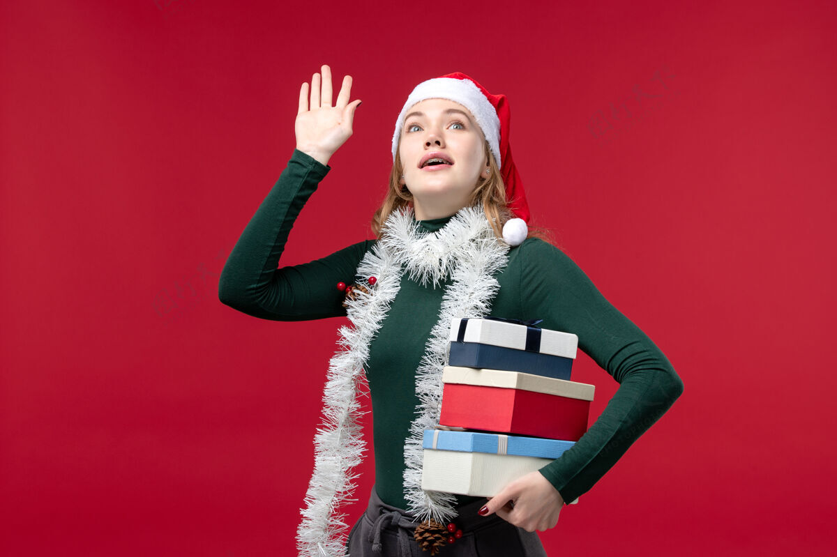 圣诞节正面图红色背景上手持新年礼物的年轻女子视图礼物黑发