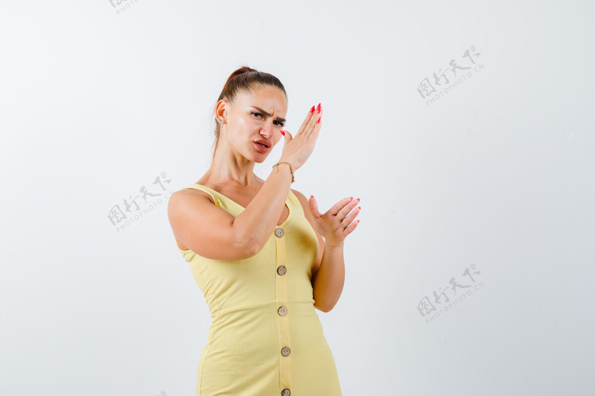人年轻女子展示空手道斩在黄色礼服的姿态 看起来恶意 前视图孤独女性手势
