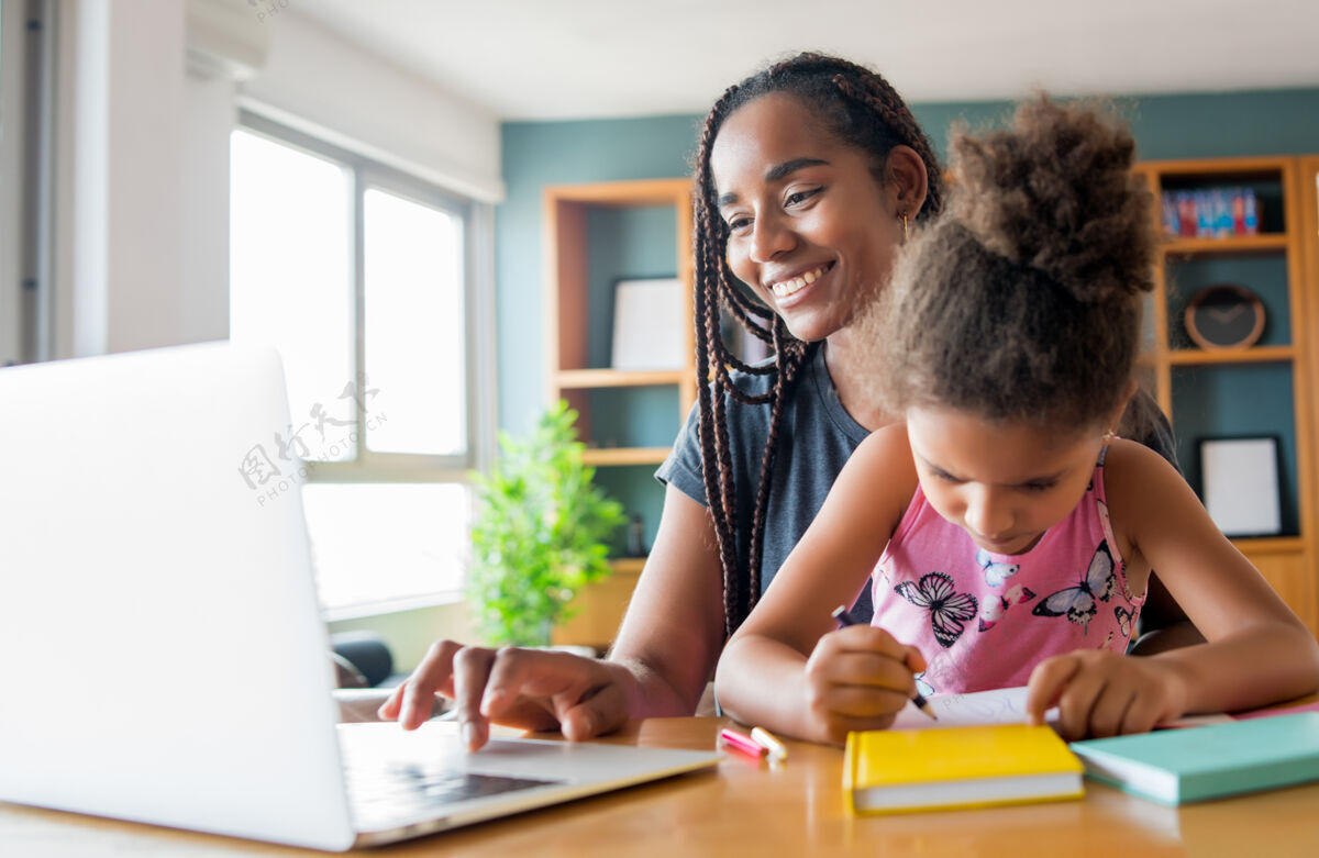 家庭母亲在家里帮助和支持女儿上网络学校新的正常生活方式理念单亲观念家庭作业笔记本电脑孩子