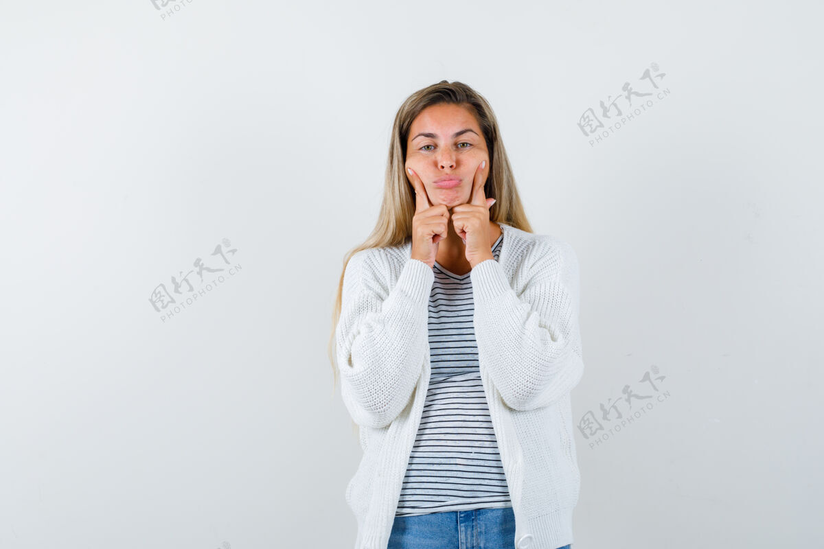 一个身穿t恤衫 夹克衫的年轻女子手指贴在脸颊上 神情阴郁 正面照时尚女孩女性