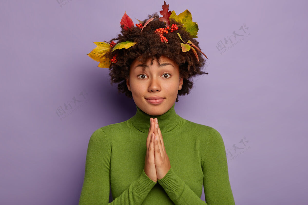 人美国黑人妇女双手合十 祈祷真诚 头发上有秋叶 穿着绿色套头衫黑发墙孤独