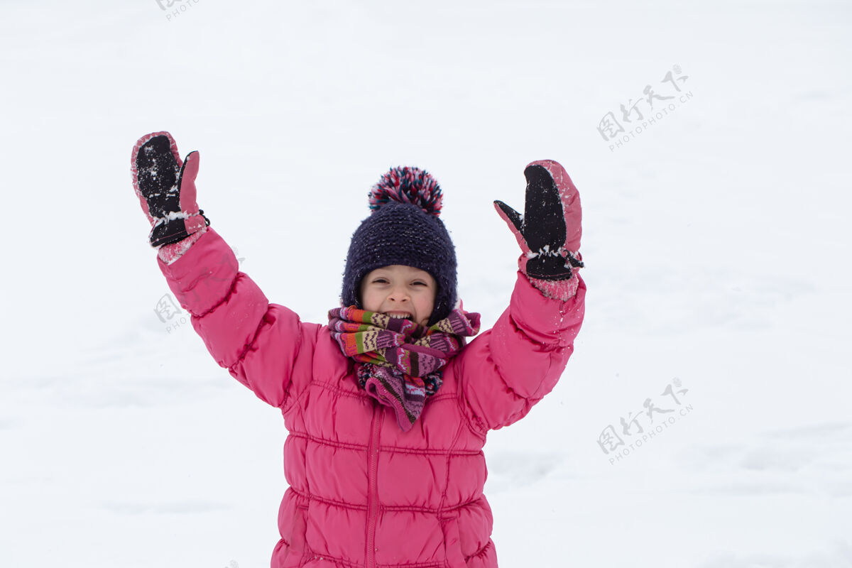 童年一个穿着粉色夹克 戴着帽子的可爱小女孩正在雪地里玩耍冬季儿童娱乐理念下雪乐趣女孩