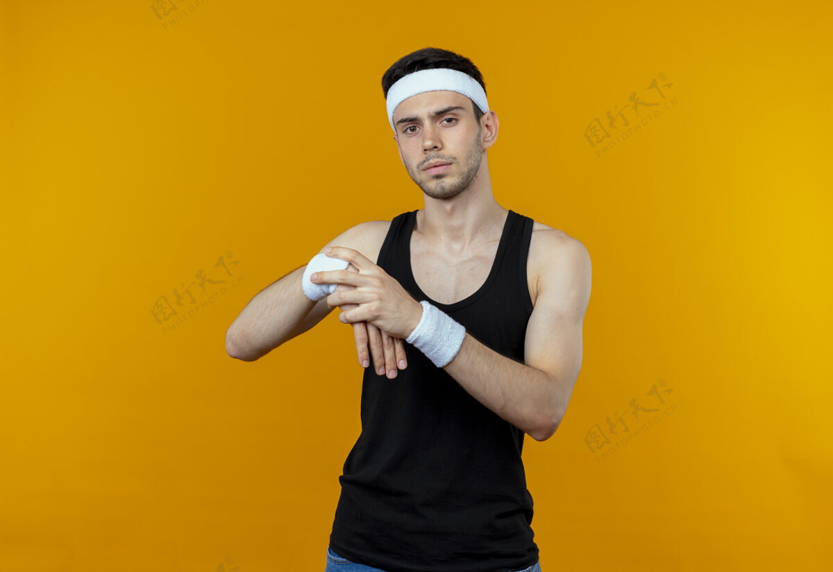 手腕戴着头巾的年轻运动型男子抚摸着手腕 把手伸到橘子上男人伸展头带