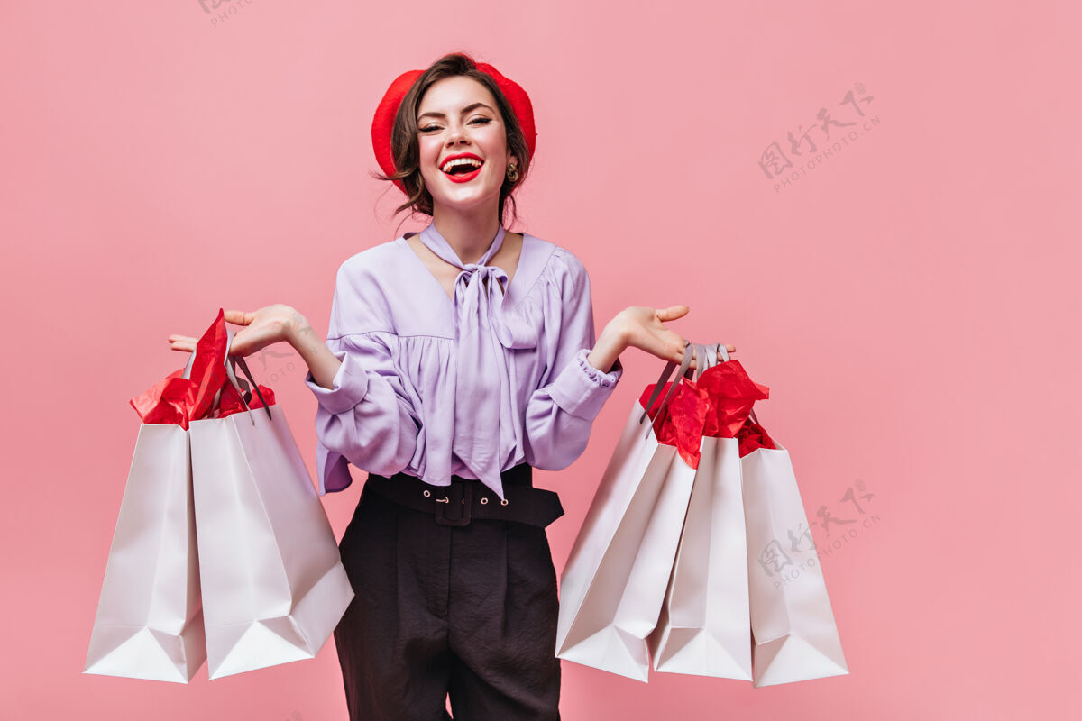 红色心情很好的女人在粉色背景下购物后 一边笑一边拿着包裹女士姿势成人