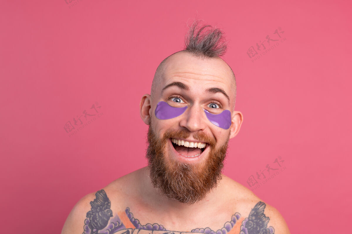 好看欧洲帅哥留着胡子纹身上身的男人戴着紫色眼罩对着镜头摆粉红色的姿势皱纹化妆品欢呼
