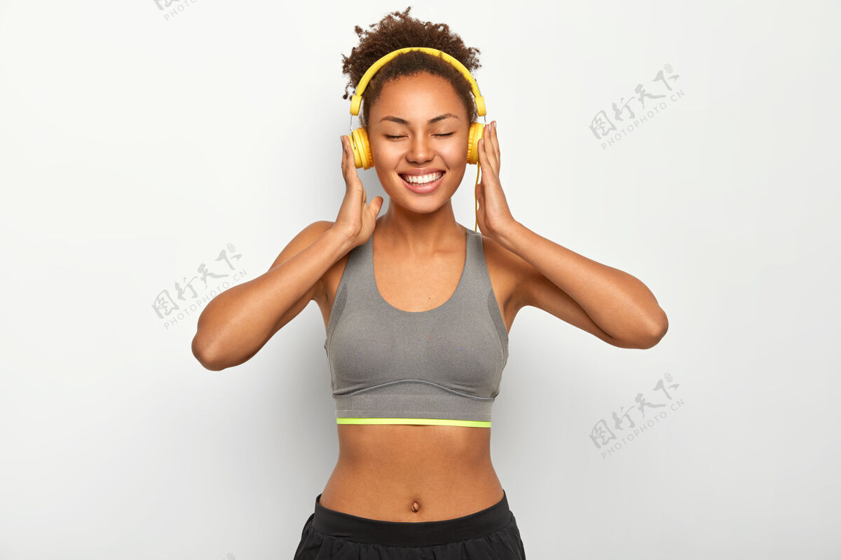 放松快乐微笑的女人运动后放松 穿着运动服 戴着现代耳机听音乐 心情愉快快乐听力休闲