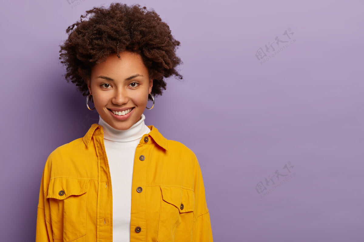 肖像卷曲的女人 温柔的微笑 温柔的表情 谈论愉快的话题 戴着耳环和时尚的黄色夹克 孤立的紫色背景女士非洲看