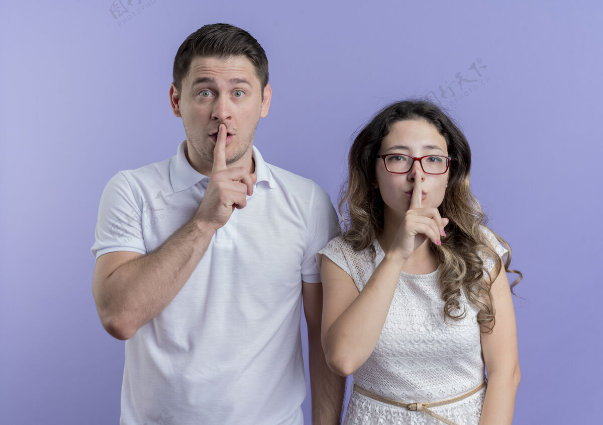 制造一对年轻夫妇用手指在蓝色的嘴唇上做着沉默的手势沉默嘴唇站立