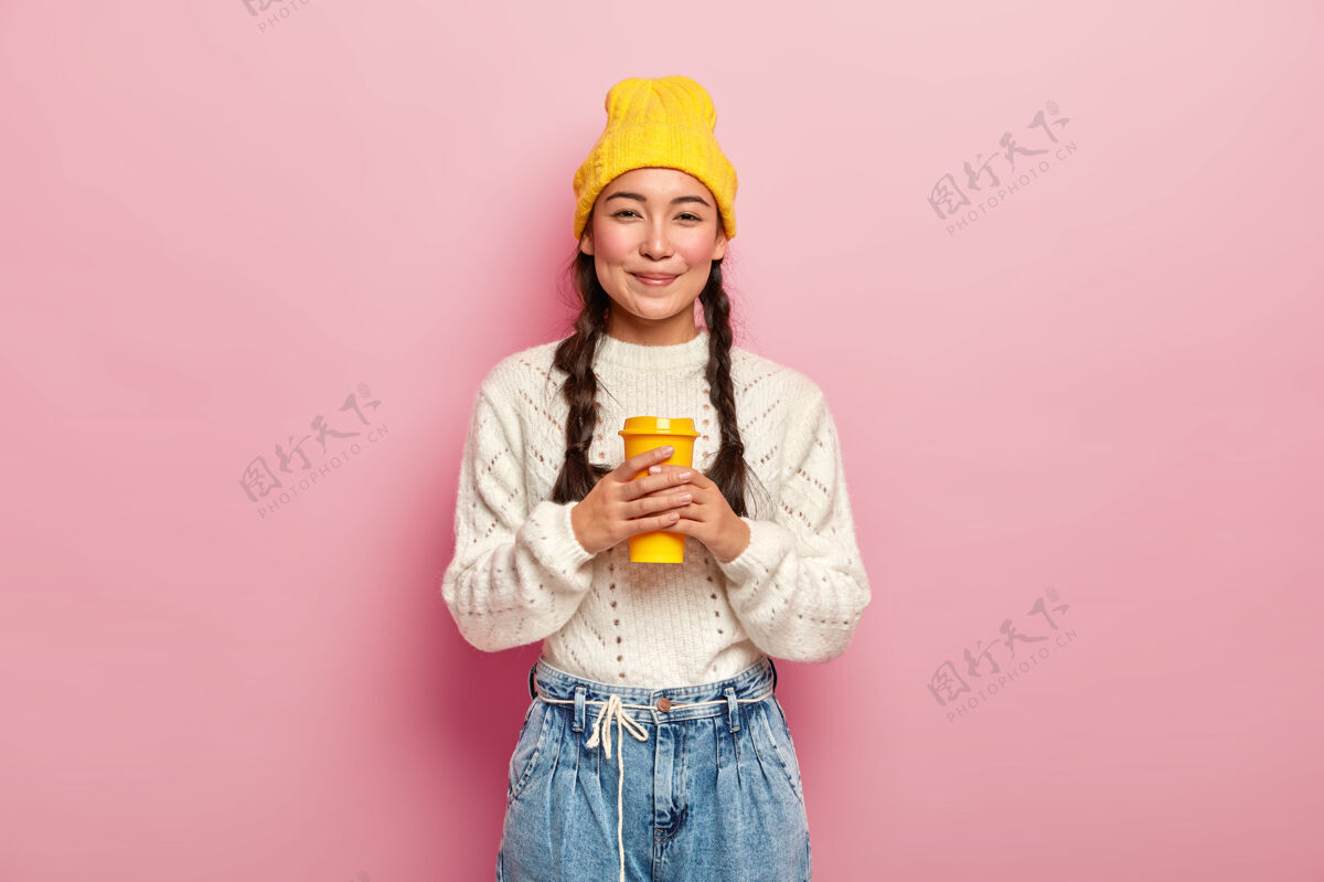 日语喜欢漂亮的女人 有辫子 穿着得体 喜欢喝外卖杯的咖啡 表情愉快 在粉红色的墙上摆姿势肖像咖啡快乐