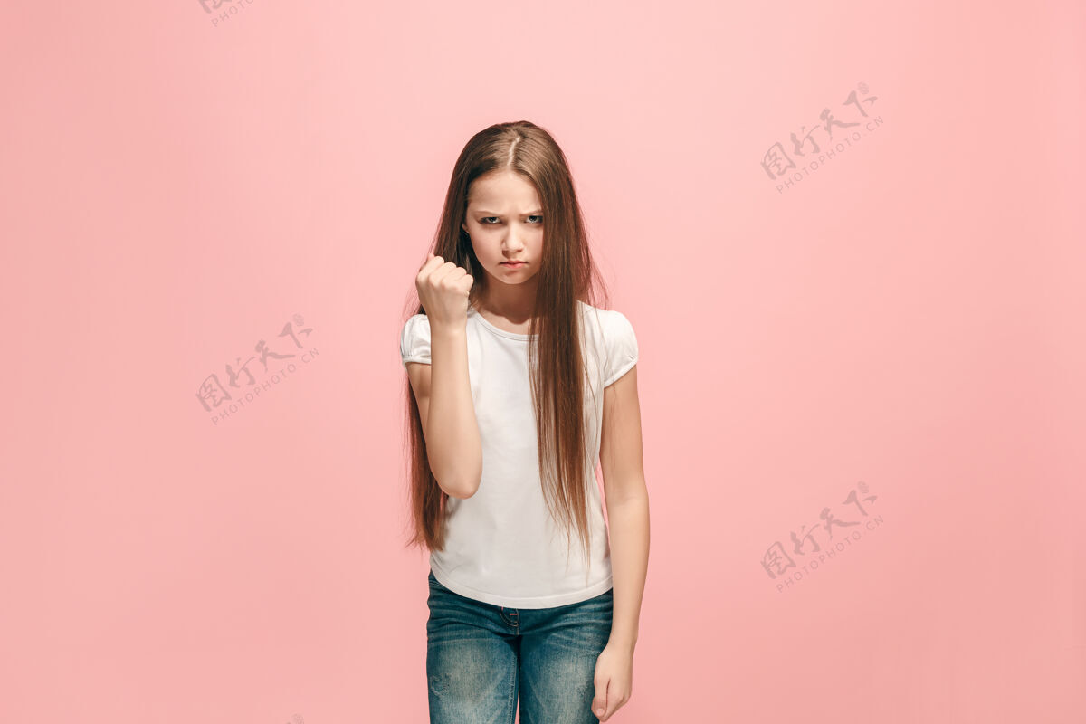 不经意愤怒的少女站在时髦的粉红色墙上女性半身像人类情感 面部表情概念正面视图青少年严重侵略性