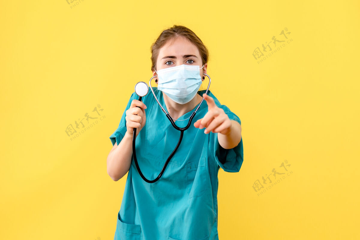 人前视图女医生戴着口罩在淡黄色背景上健康病毒大流行器械设备高尔夫球手