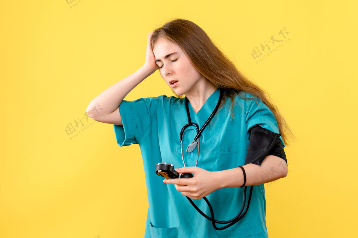 医院正面图黄色背景女医生测量压力医疗卫生院护士诊所听诊器
