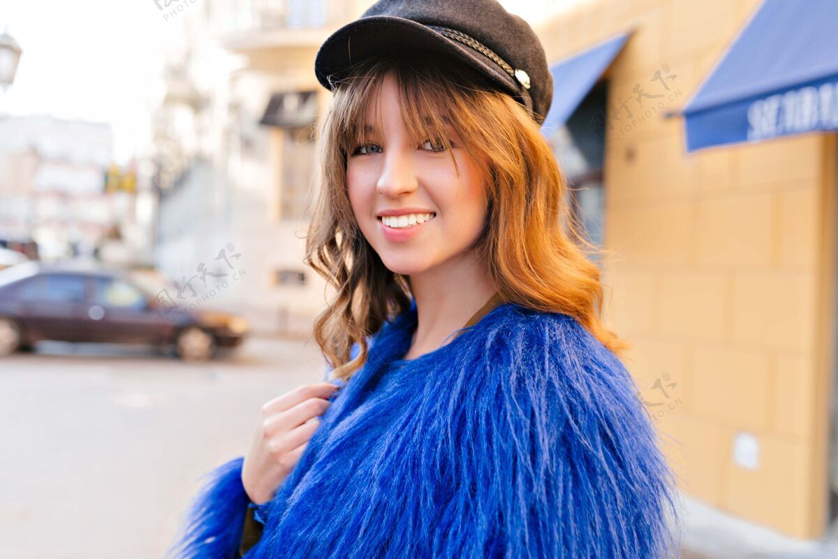 街街街风格迷人可爱的女人的肖像 带着迷人的微笑 波浪形的头发 穿着蓝色的皮草 戴着黑色的帽子休闲模特魅力