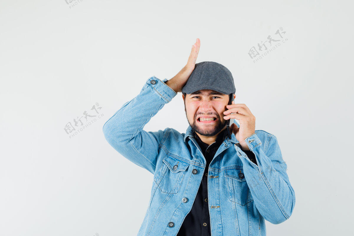 手机复古风格的男人穿着夹克 帽子 衬衫在手机上聊天 看起来很麻烦正面图手机帽子年轻