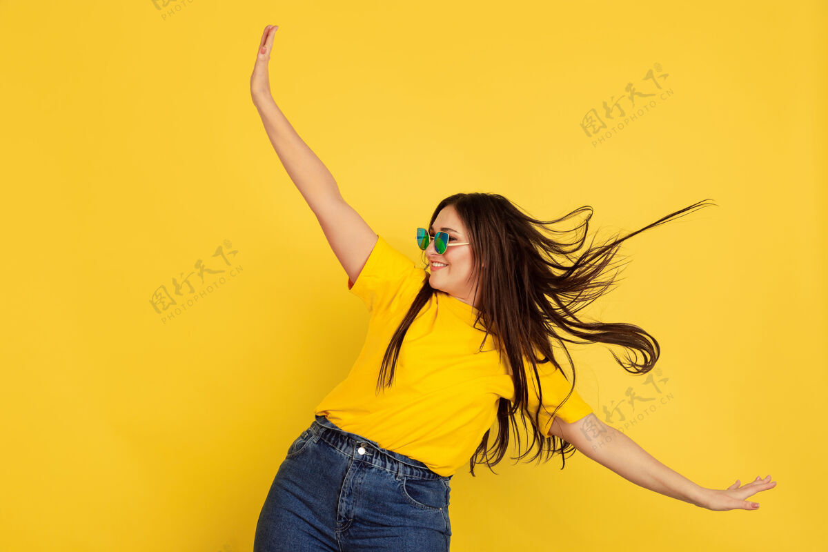 职业灵感来自于戴着太阳镜的舞蹈黄色墙壁上的白种女人休闲风格的漂亮的深色女性模特人类情感的概念 面部表情 销售 广告 广告空间女孩现代公司