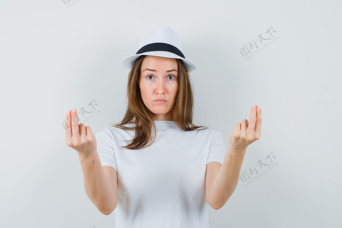 随意穿着白色t恤 戴着帽子 看起来很懂事的年轻女孩在做金钱手势正面视图小金钱姿态