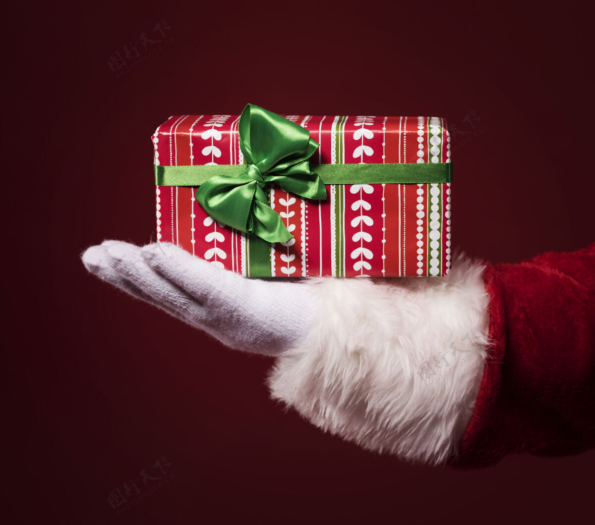 彩色圣诞老人手里拿着一个红色背景的礼品盒圣诞节手套不认识的人