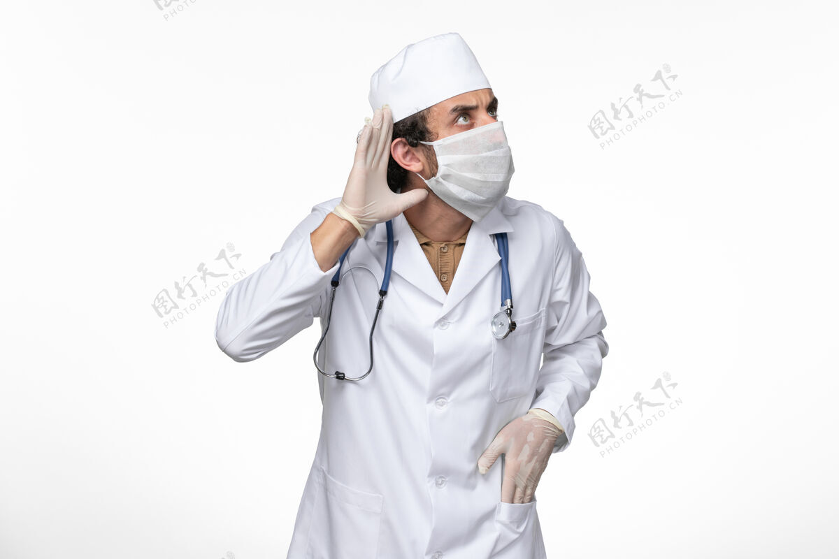 面罩正面图男医生穿着医疗服 戴着无菌口罩 以防感染柯维德病毒-试图听到白墙病毒疾病柯维德大流行疾病防护服冠状病毒正面