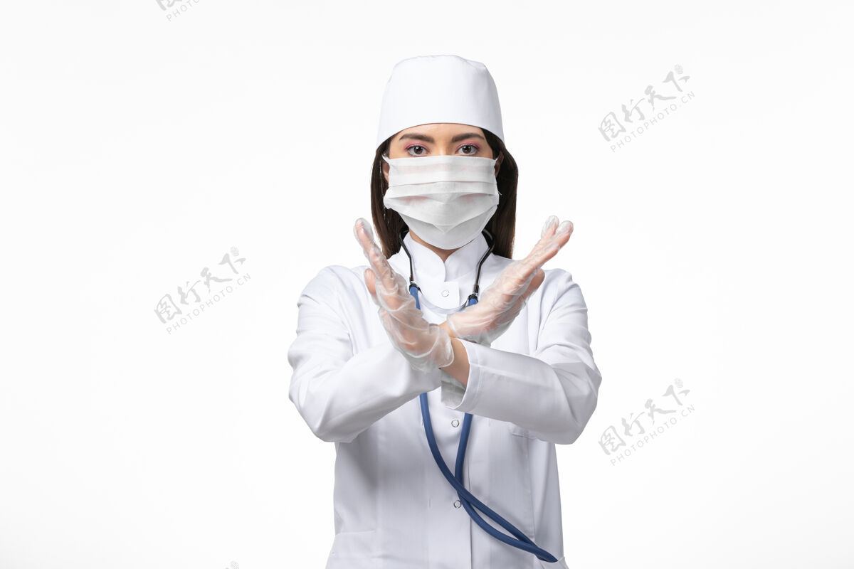 病毒正面图：女医生穿着白色无菌医疗服 带口罩 因柯维德-白墙疾病显示禁止标志柯维德-大流行病毒疾病到期医疗正面
