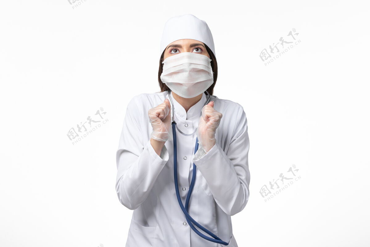 视图正面图女医生身穿白色无菌医疗服 带口罩 因冠状病毒轻染白墙病大流行冠状病毒面罩冠状病毒病毒