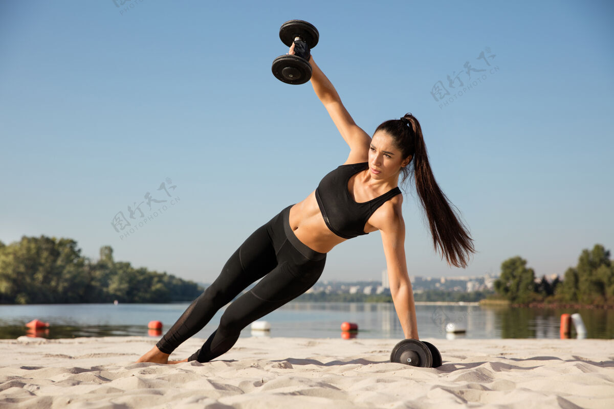 健身年轻健康的女子在沙滩上练习上身举重肌肉运动练习