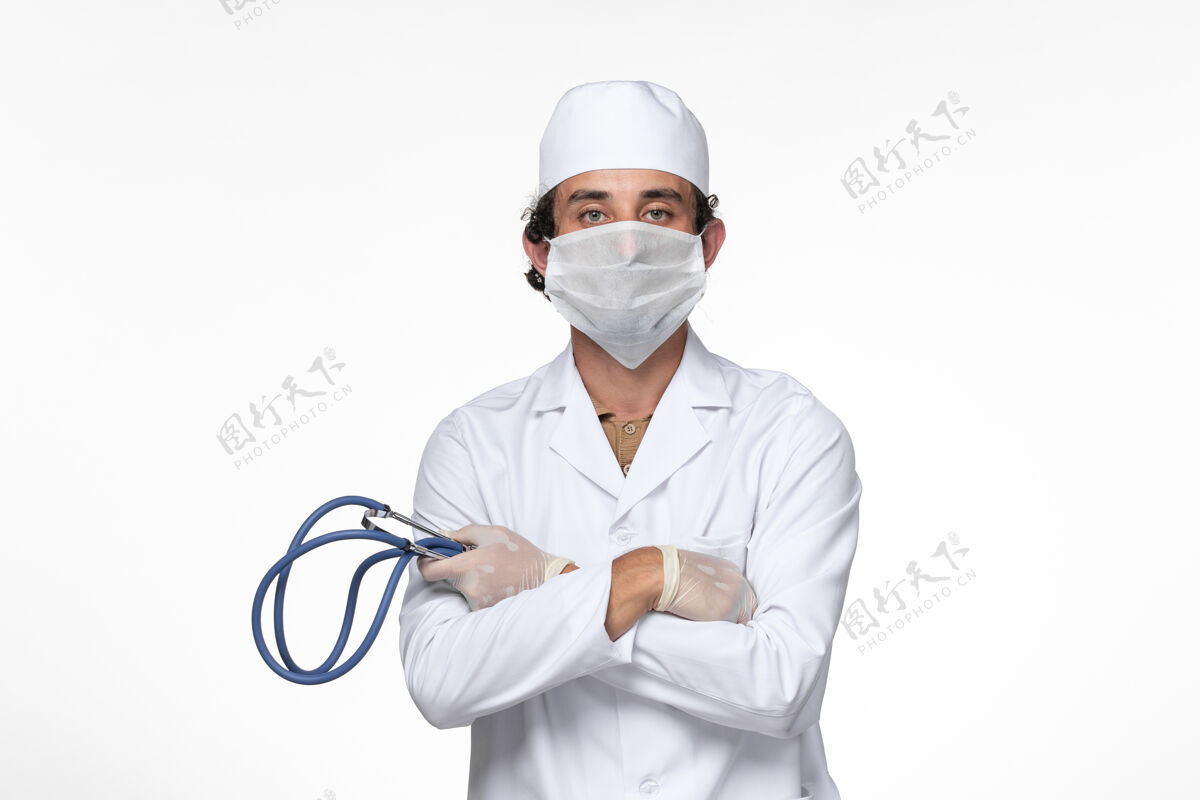 冠状病毒预防正面图身穿医疗服的男医生戴着口罩 以防白墙病毒疾病的传播视图正面冠状病毒防护