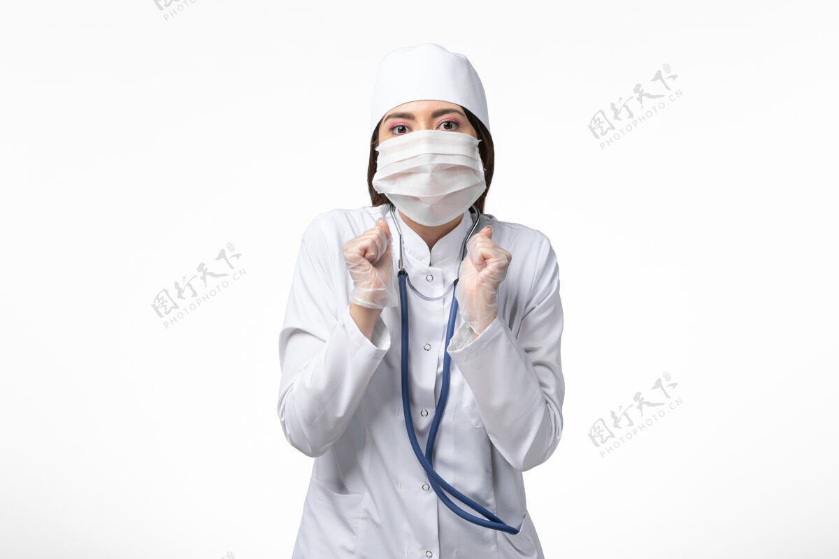 套装正面图女医生身穿白色无菌医疗服 带口罩 因白桌上冠状病毒病大流行冠状病毒疾病专业听诊器
