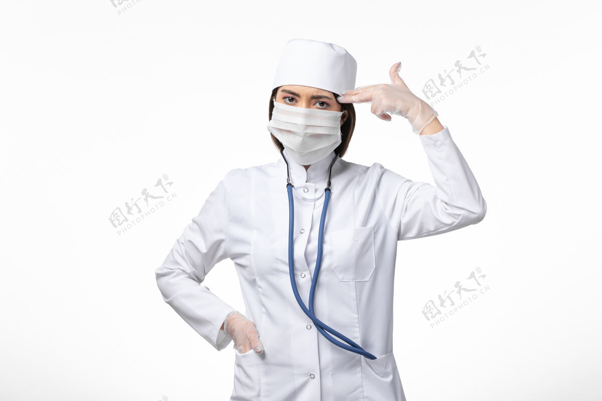 视图正面图女医生身穿白色无菌医疗服 带口罩 因白墙上冠状病毒病冠状病毒-大流行病毒实验室外套服装冠状病毒