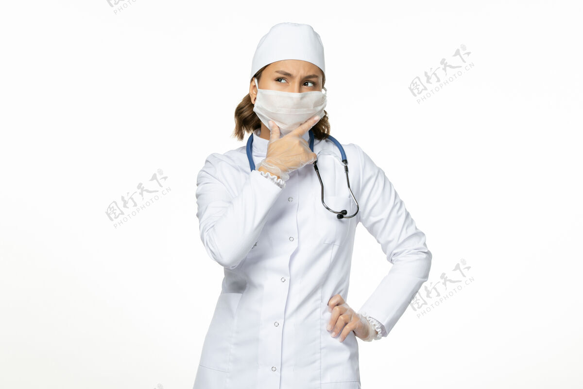 思考正面图女医生穿着白色医疗服 戴着口罩 因冠状病毒思考白墙大流行病毒病视图大流行女性