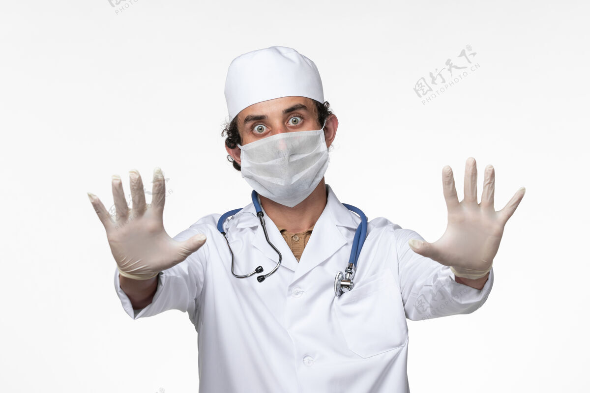 冠状病毒预防正面图：男医生穿着医疗服 戴着口罩 以防白墙病毒的传播男人正面医疗