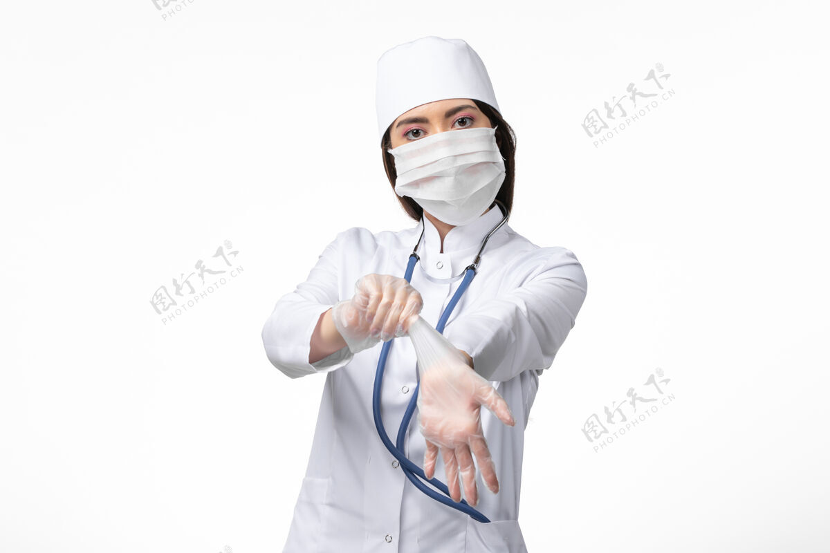 人员正面图女医生身穿白色无菌医疗服 带口罩 因冠状病毒轻染白墙病大流行病毒covid-疾病病毒灭菌