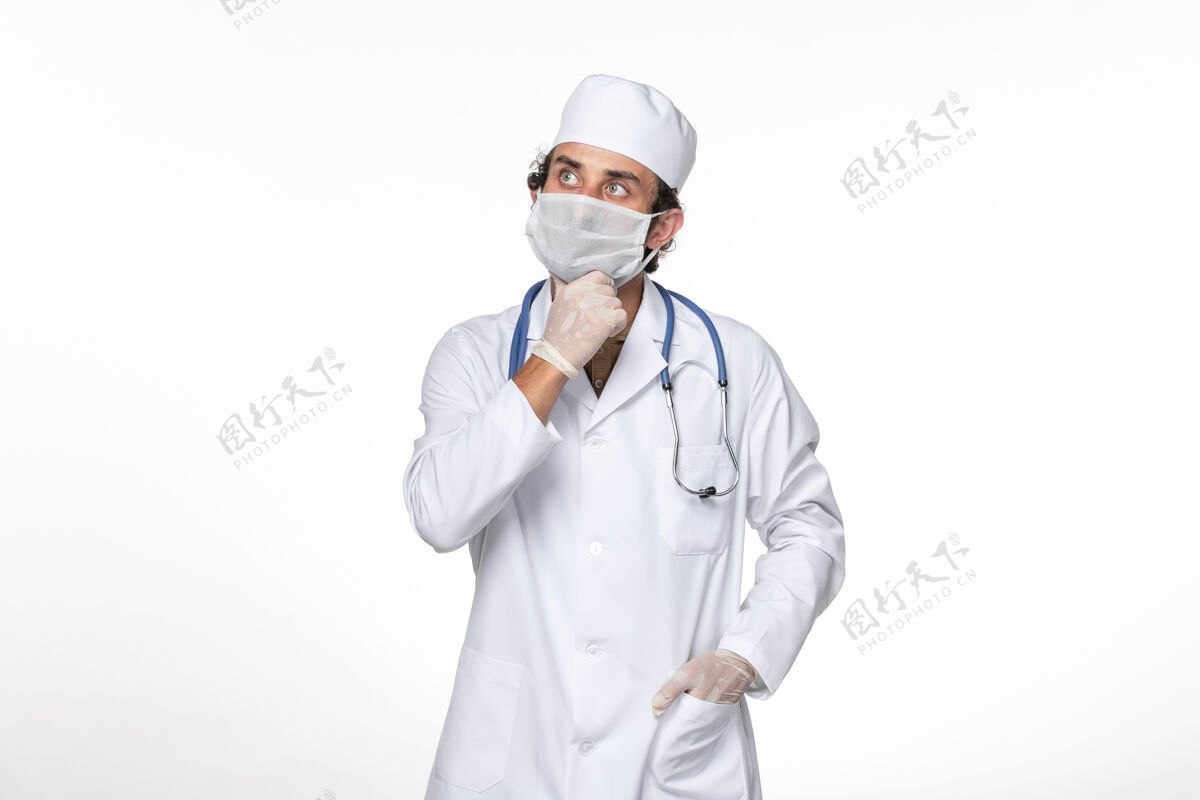外套正面图戴口罩的男医生穿着医疗服 以防感染冠状病毒——关于白墙冠状病毒大流行医学的思考冠状病毒医学视图