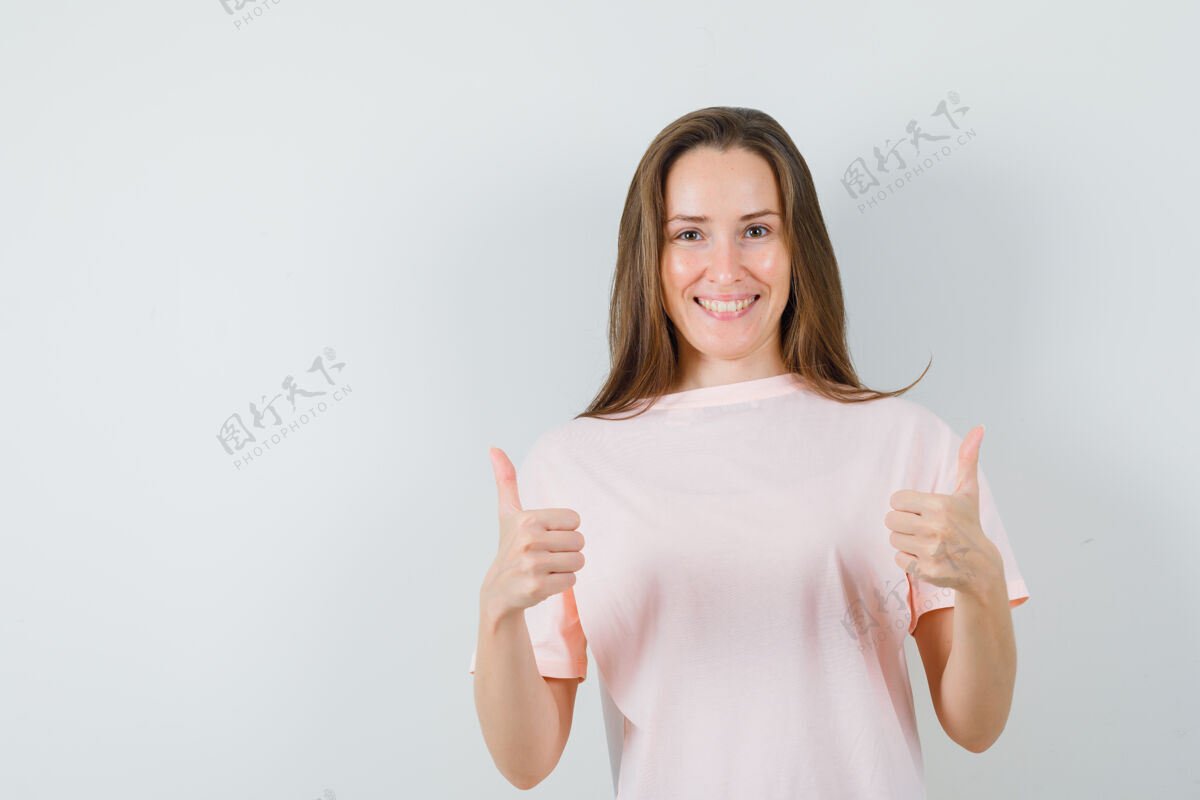 双人穿着粉色t恤的年轻女孩向上竖起大拇指 看上去很高兴正面图快乐漂亮休闲