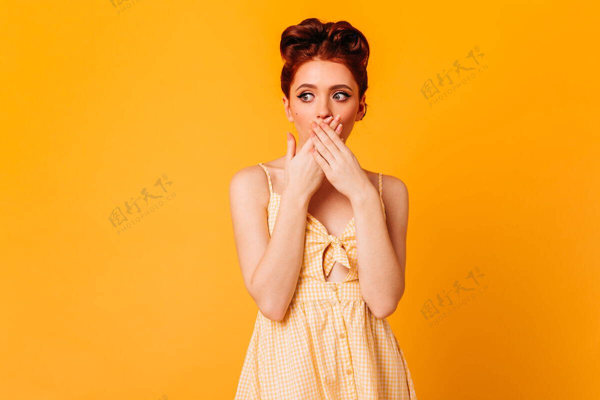 诱惑性感的姜黄色女人用手捂着嘴黄色空间里的时尚女性模特的摄影棚镜头女性积极服装