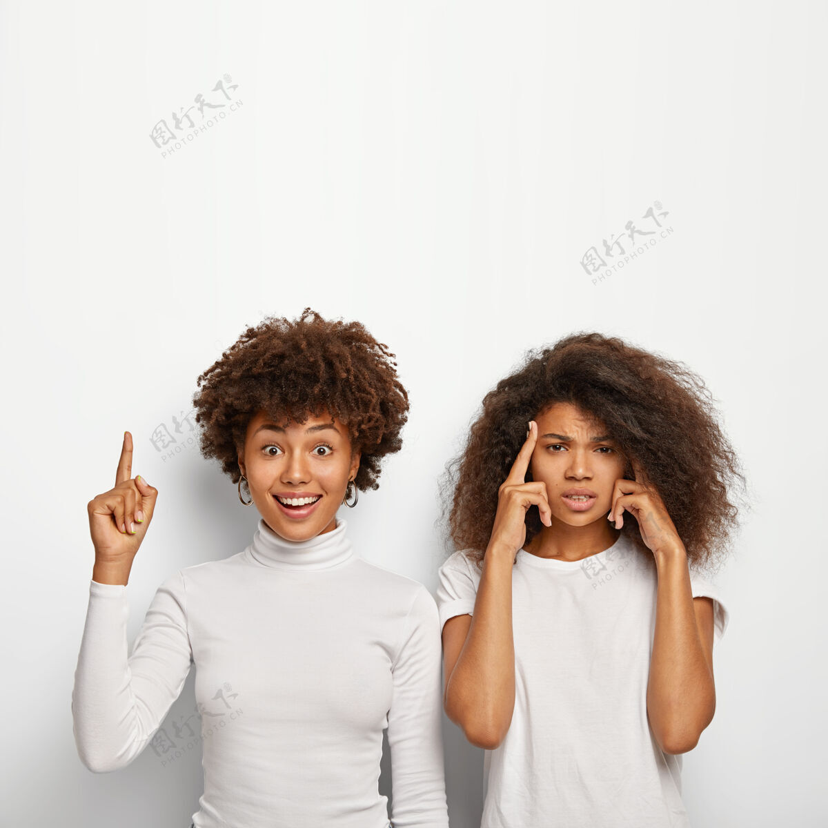 太阳穴快乐的非裔美国妇女指着食指上方 她热情的朋友抚摸着太阳穴 试图回忆起重要的信息指向室内女人