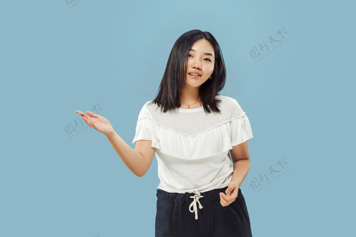 女性蓝色空间上的韩国年轻女子半身像穿白衬衫的女模特展示并指向某物手工作面部