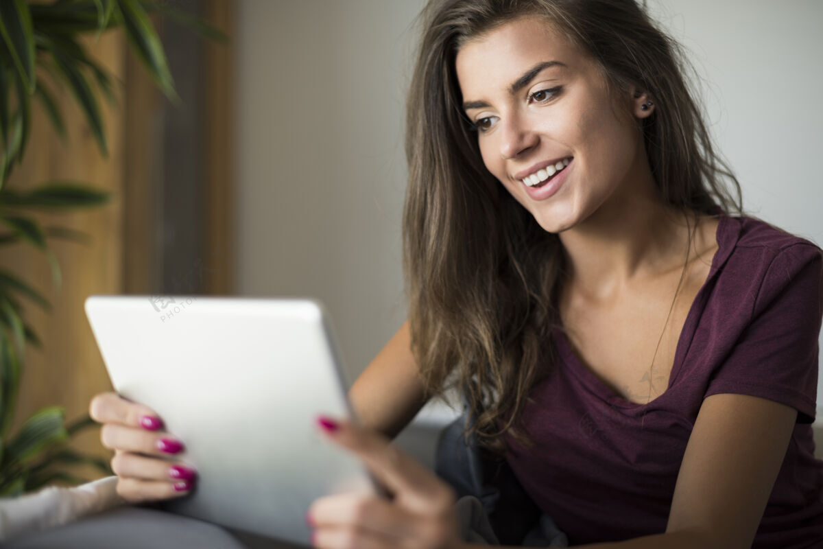 现代快乐的年轻女子与数字平板电脑客厅快乐沙发