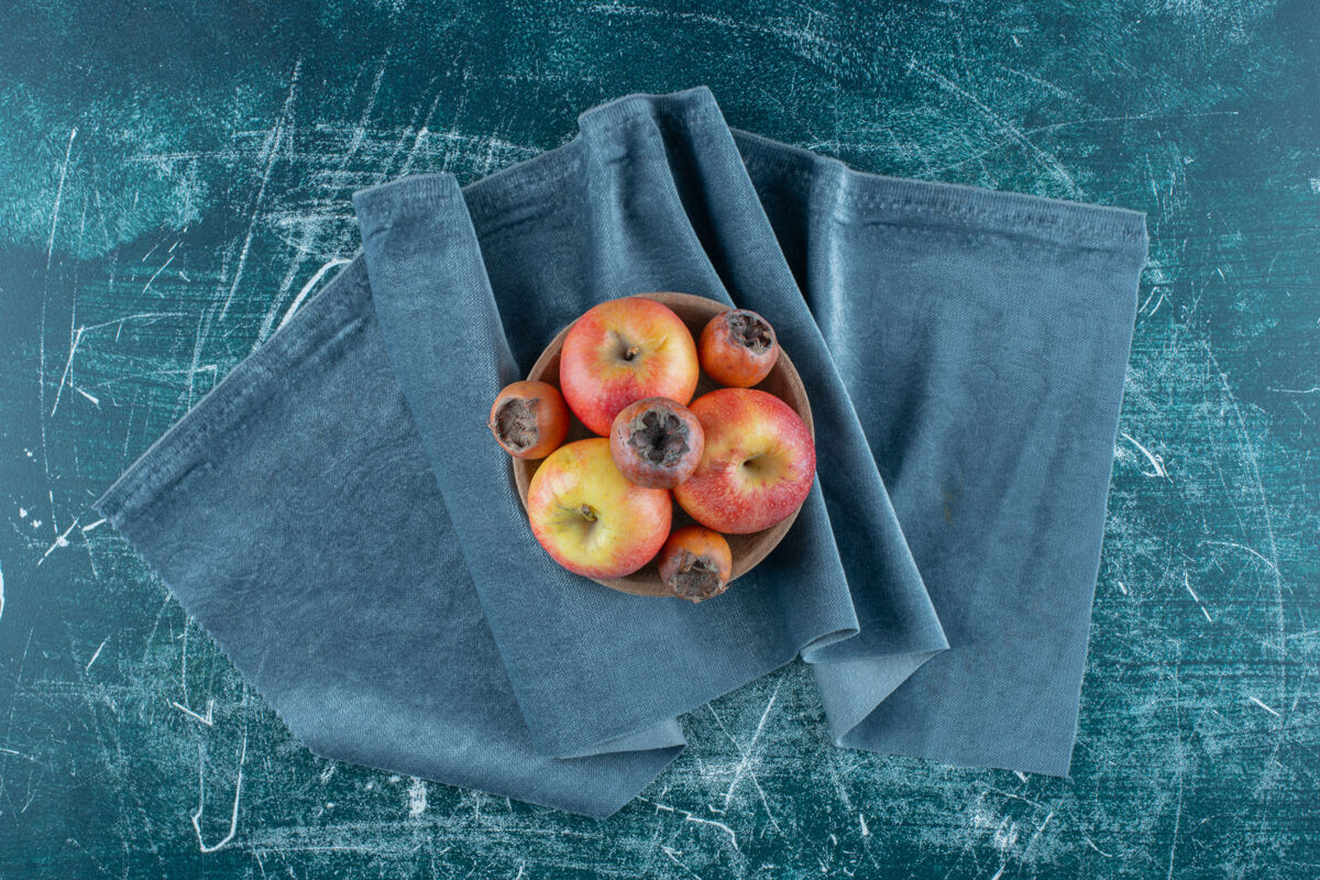 毛巾一小包枸杞果和苹果在碗里 在毛巾上 在蓝色的背景上高质量的照片天然水果新鲜