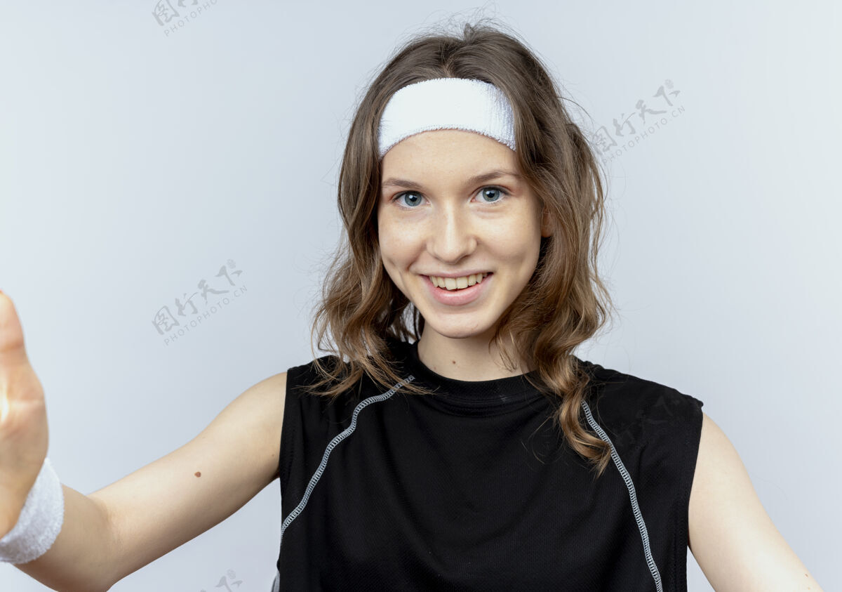 脸身穿黑色运动服 头戴头巾 严肃的脸 双臂交叉的年轻健身女孩站在白墙上健康运动装年轻