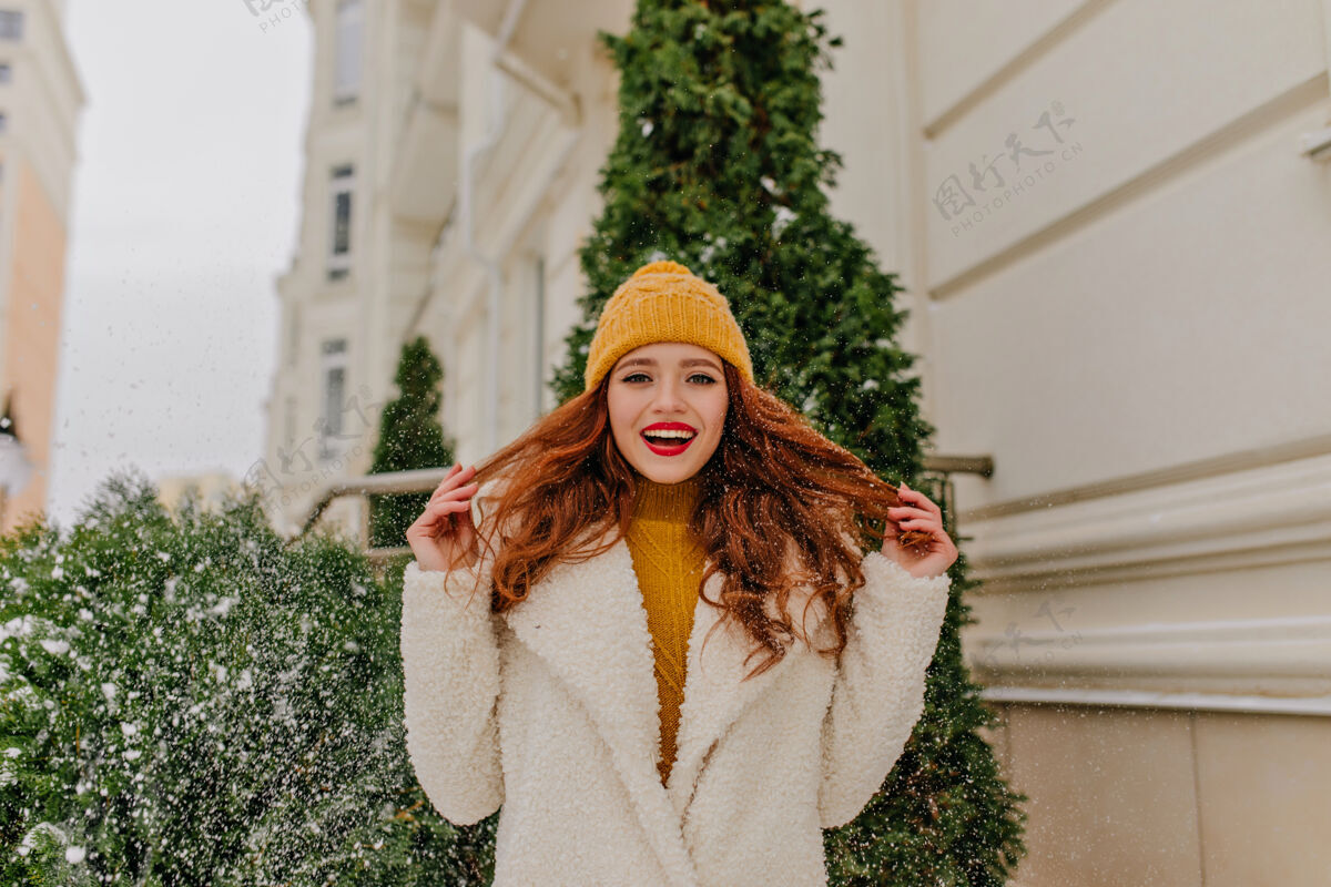 脸迷人的微笑女孩在冬天玩她的姜黄色头发令人惊叹的欧洲女士站在绿色冷杉附近的户外照片时尚云杉女士