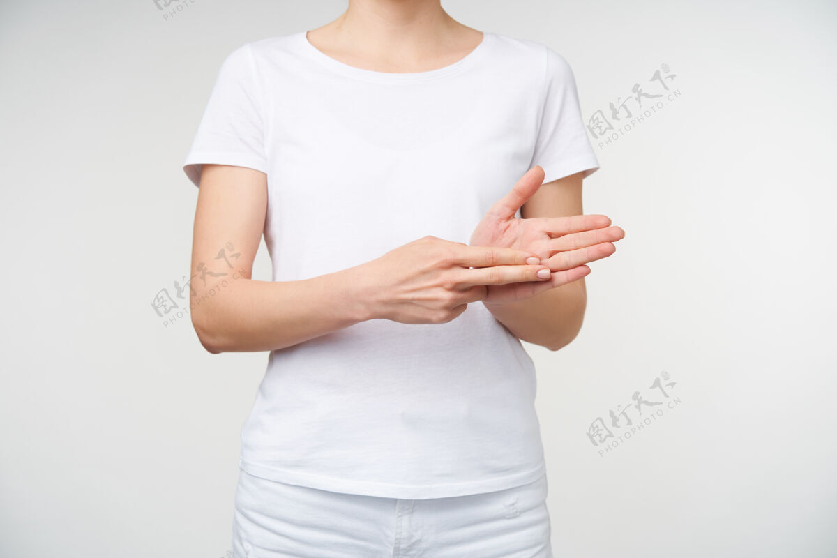 女士摄影棚拍摄的年轻女子举起双手 同时展示单词train使用聋人的语言 隔离在白色背景下的休闲服站立T恤翻译