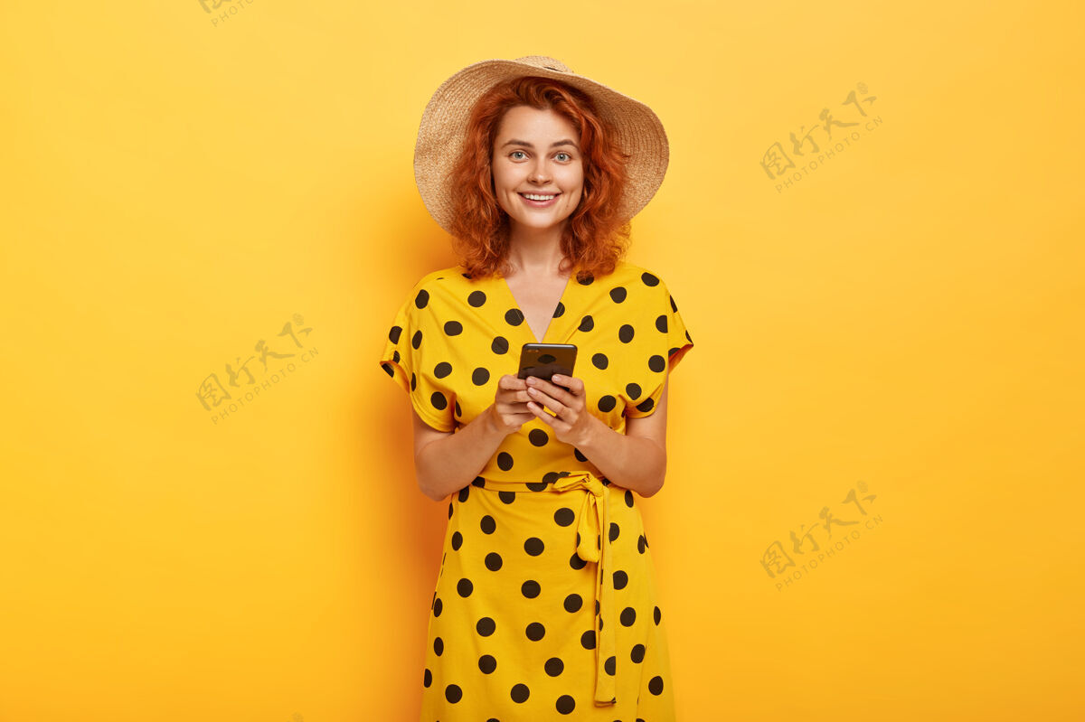 衣服室内拍摄的红发女子摆出黄色波尔卡裙和草帽稻草举行波尔卡多